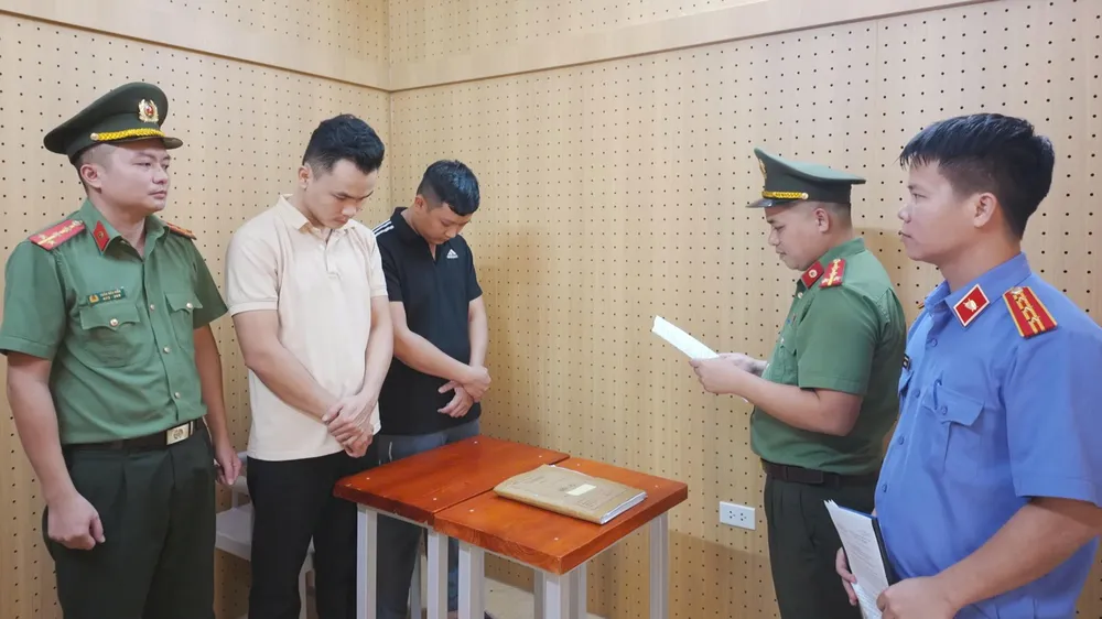 Cơ quan An ninh điều tra Công an tỉnh Hà Tĩnh tống đạt quyết định khởi tố bị can, thi hành lệnh tạm giam đối với Đặng Hoàng Lợi và Đặng Hùng Vương. Ảnh: BÙI HẢI