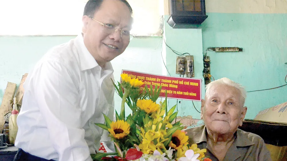Ủy viên Trung ương Đảng, Phó Bí thư Thường trực Thành ủy TPHCM Tất Thành Cang trao tặng đồng chí Lý Toàn Anh Huy hiệu 70 năm tuổi Đảng