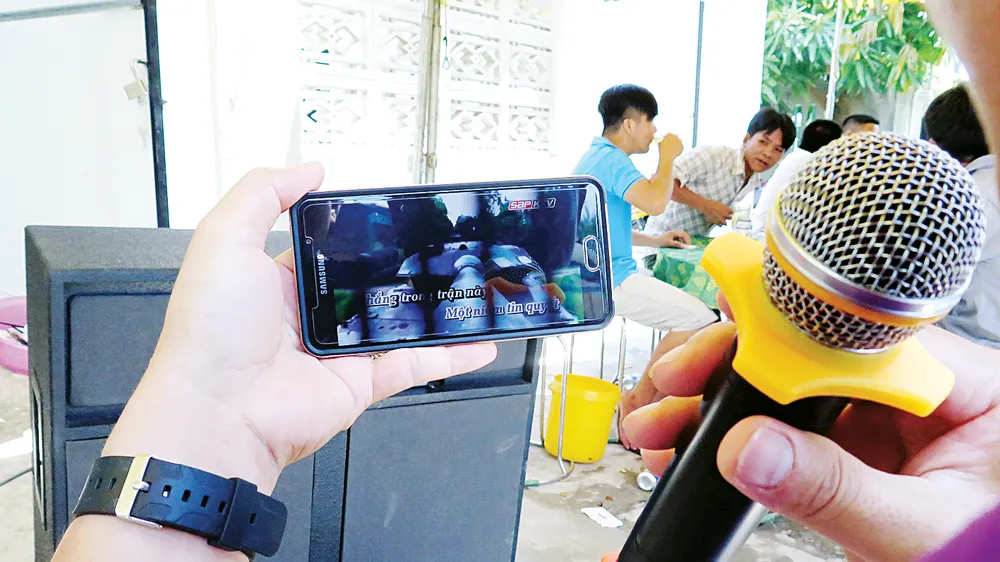 Một đám tiệc, chỉ cần dàn loa, micro kết nối phần mềm karaoke trên điện thoại di động, là đủ hành hạ làng xóm . Ảnh: DŨNG PHƯƠNG