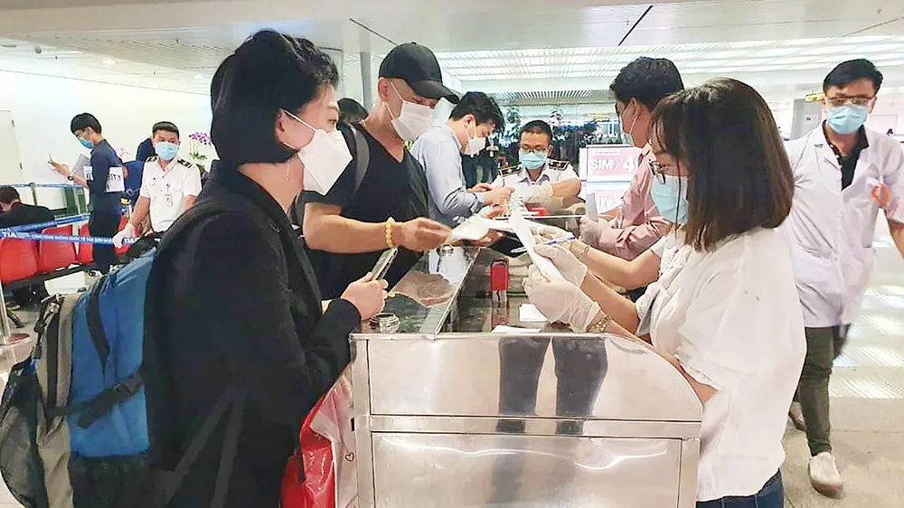 Khách từ Hàn Quốc thực hiện tờ khai y tế tại sân bay Tân Sơn Nhất rạng sáng 24-2. Ảnh: THÀNH SƠN