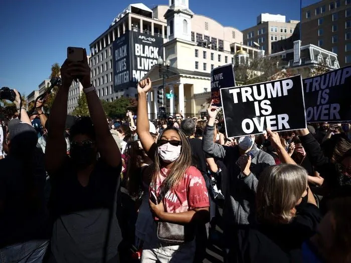 Một số người mang theo cờ Mỹ bà biển hiệu: "Trump đã kết thúc". Nguồn: REUTERS