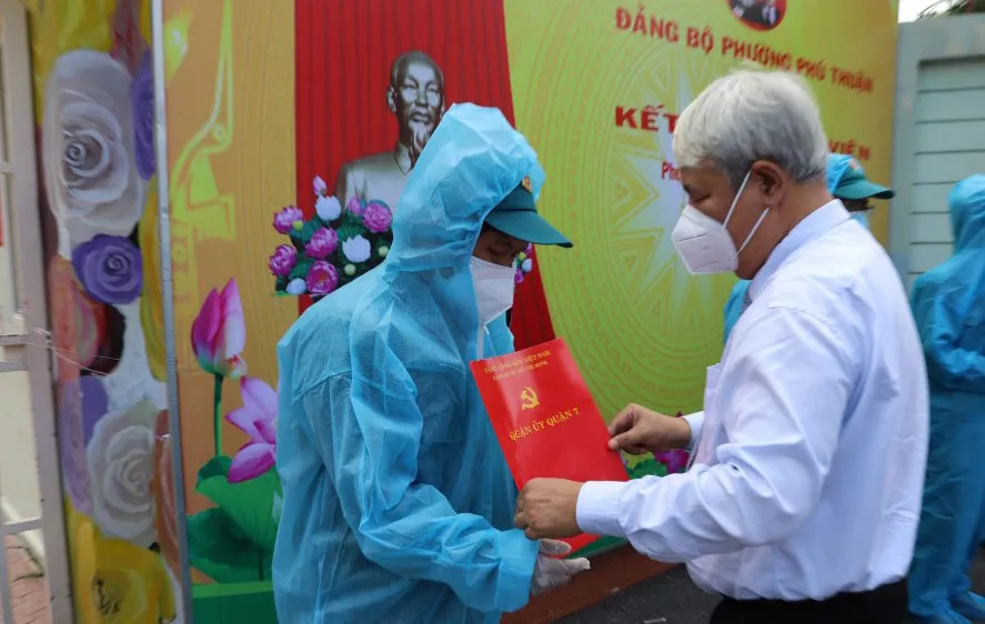Bí thư Quận ủy quận 7 Võ Khắc Thái trao quyết định kết nạp Đảng cho đảng viên mới tại điểm cách ly ở Trường Mầm non Phú Thuận. Ảnh: GIA BẢO
