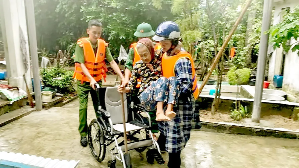 Lực lượng vũ trang tỉnh Quảng Nam hỗ trợ người già yếu đến nơi an toàn. Ảnh: MINH HUY