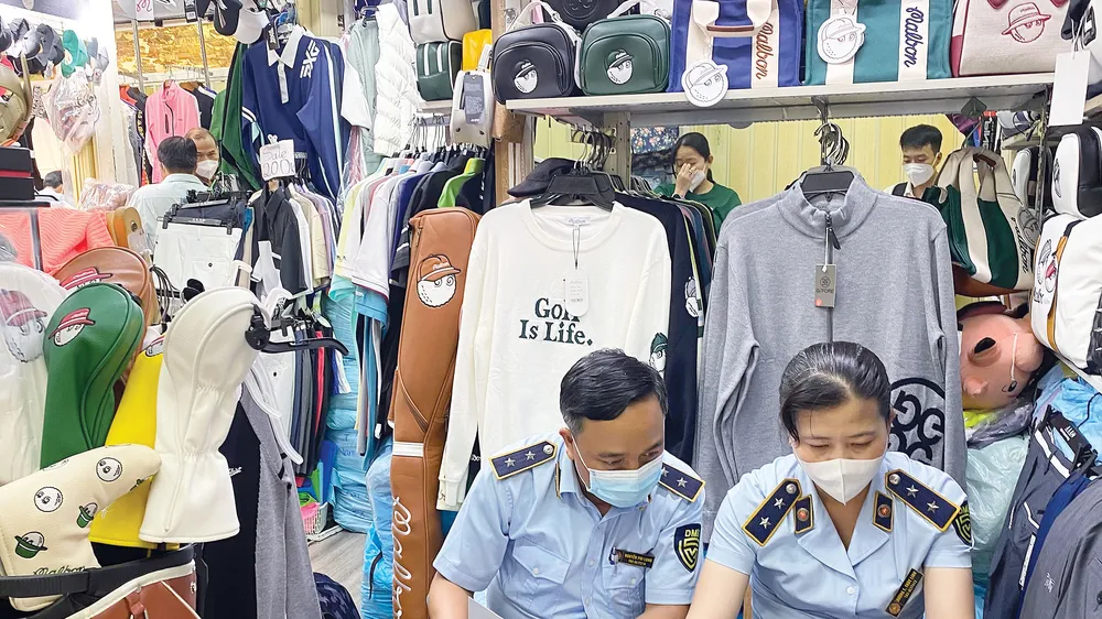 Quản lý thị trường kiểm tra, lập biên bản cửa hàng vi phạm tại Saigon Square, TPHCM. Ảnh: BÙI ANH TUẤN