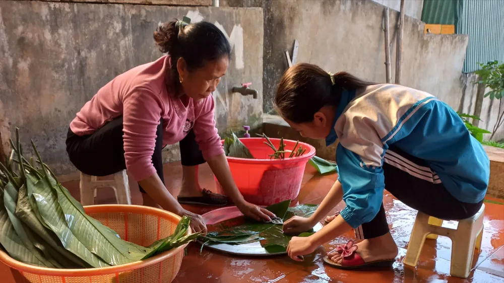 Bà ngoại cùng cháu rửa lá dong chuẩn bị gói bánh chưng đón tết
