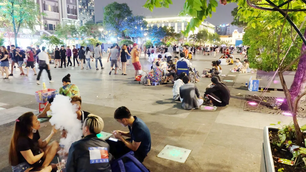 Người trẻ vô tư ngồi bệt ở phố đi bộ Nguyễn Huệ (quận 1) để ăn uống và xả rác