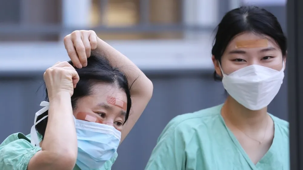 Nhân viên y tế sử dụng băng cá nhân để che vết thương trên mặt do đeo kính bảo hộ trong nhiều giờ trong khi điều trị cho bệnh nhân nhiễm Covid-19 tại Bệnh viện Dongsan ở Daegu vào ngày 4-3. Ảnh: Yonhap