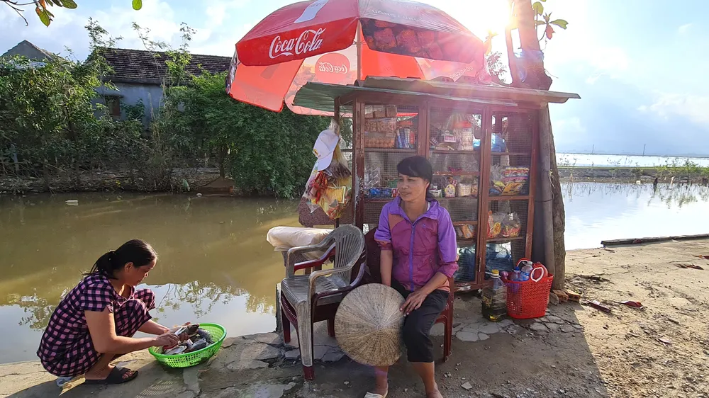 Chị Lê Thị Trang bên quán tạp hóa nhỏ ven bờ kênh. Ảnh: MINH PHONG