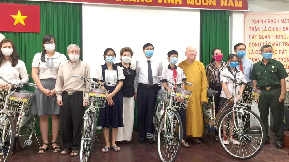 Chị Đặng Thị Minh Nguyệt (thứ tư, từ trái sang) tặng phương tiện đi học cho học sinh, sinh viên hoàn cảnh khó khăn