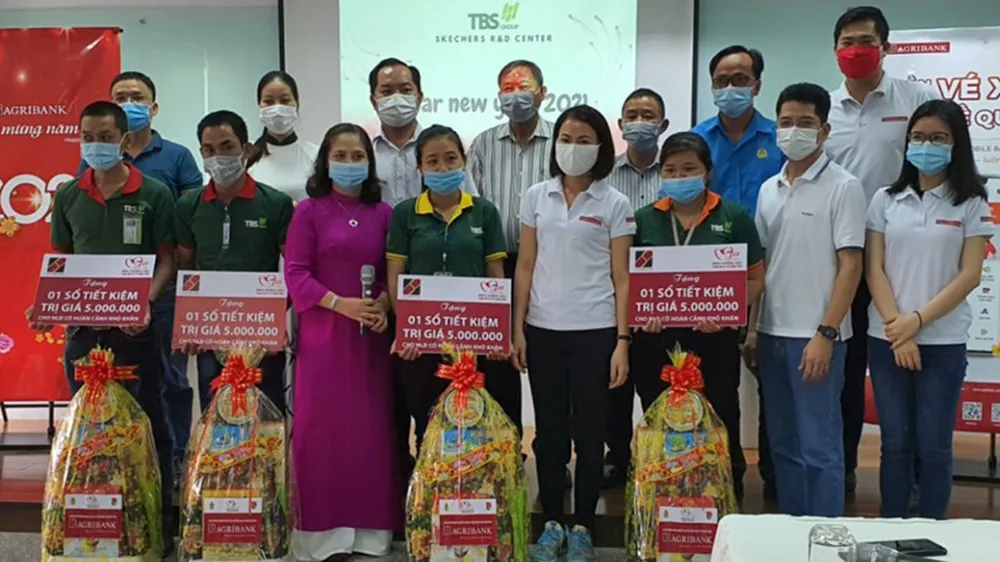 Bà Trần Thị Quỳnh Châu - Phó Giám đốc Agribank Bình Dương (thứ tư hàng đầu từ bên phải) tặng quà và sổ tiết kiệm cho công nhân có hoàn cảnh đặc biệt khó khăn của công ty TBS group