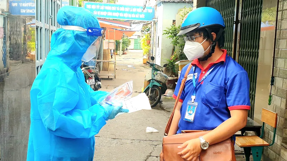 Anh Châu Tiến Lộc (phải), cán bộ Thành đoàn TPHCM, cùng nhân viên y tế nắm tình hình F0 điều trị tại nhà