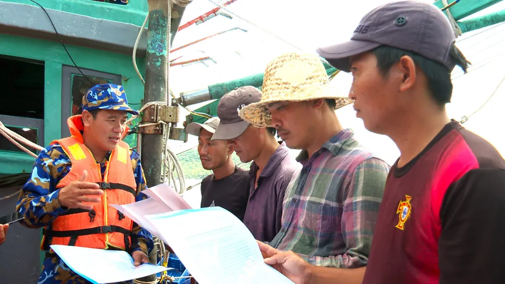 Thành viên đoàn công tác Vùng 5 Hải quân phát thư kêu gọi chống khai thác IUU cho ngư dân. Ảnh: VĂN ĐỊNH