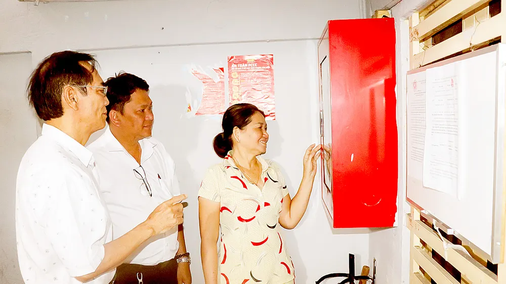 Ông Nguyễn Văn Quang (bìa trái), Bí thư Chi bộ Khu phố 4, phường 14, quận 5 hướng dẫn người dân chung cư tại khu phố sử dụng tủ PCCC. Ảnh: THÁI PHƯƠNG