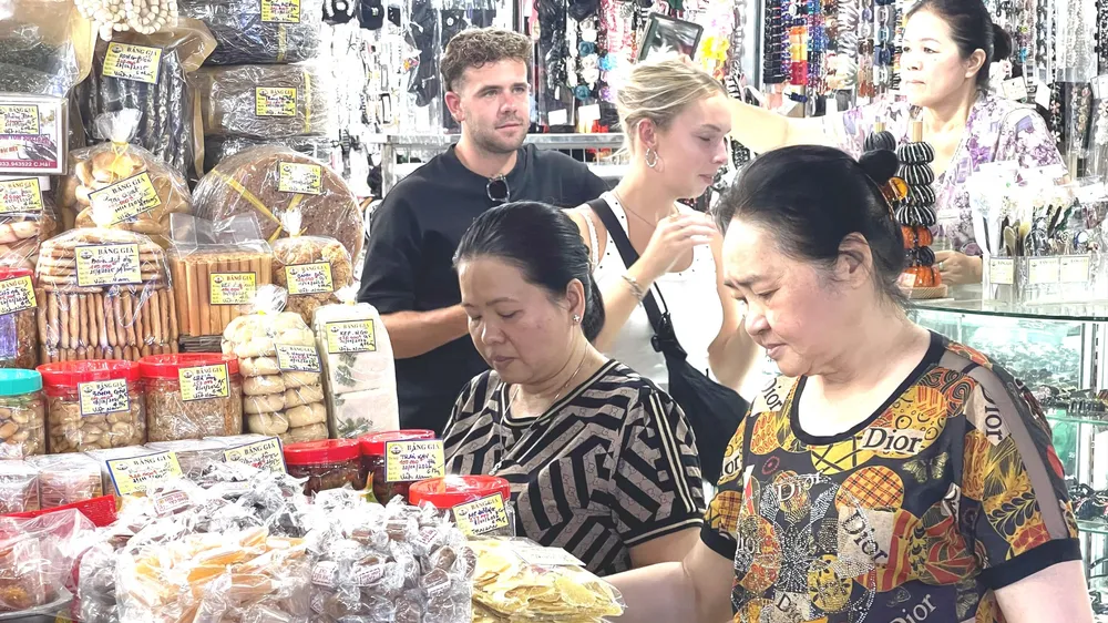 Người dân và du khách mua sắm các mặt hàng đặc sản, quà lưu niệm tại chợ Bến Thành. Ảnh: HOÀNG HÙNG