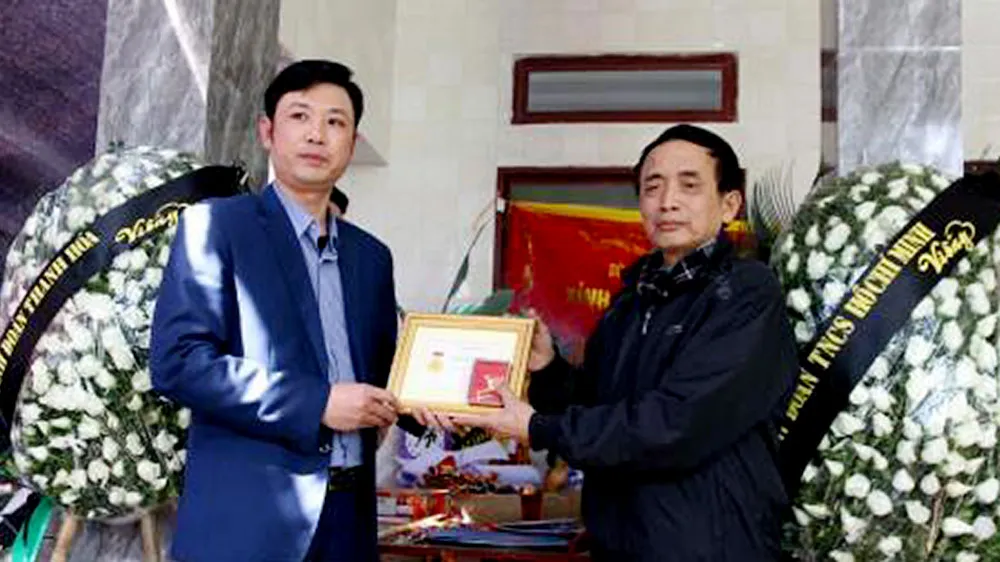 Bí thư Tỉnh đoàn Thanh Hóa Lê Văn Trung truy tặng Huy hiệu “Tuổi trẻ dũng cảm” cho thân nhân em Hoàng Đức Hải. Ảnh: TTXVN
