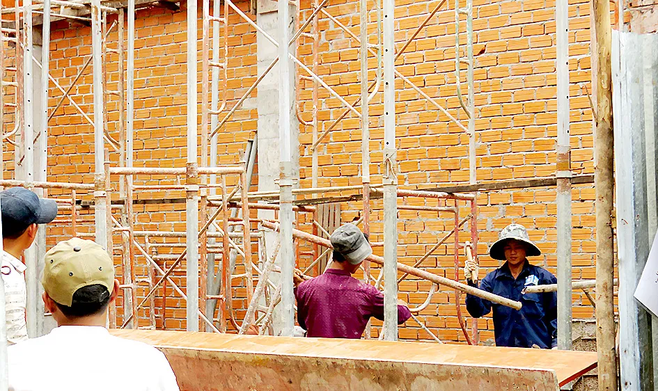Công nhân xây dựng làm việc dưới giàn giáo nhưng không được trang bị đồ bảo hộ. Ảnh: THÁI PHƯƠNG