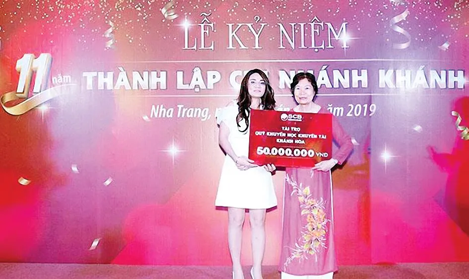 Bà Ninh Thị Quỳnh Thơm - Quyền Giám đốc SCB Khánh Hòa (áo trắng) trao tặng 50 triệu đồng cho đại diện Quỹ Khuyến học khuyến tài Khánh Hòa - Tiến sĩ Bùi Thị Hồng Tiến - Giám đốc Quỹ Khuyến học khuyến tài Khánh Hòa (áo dài)