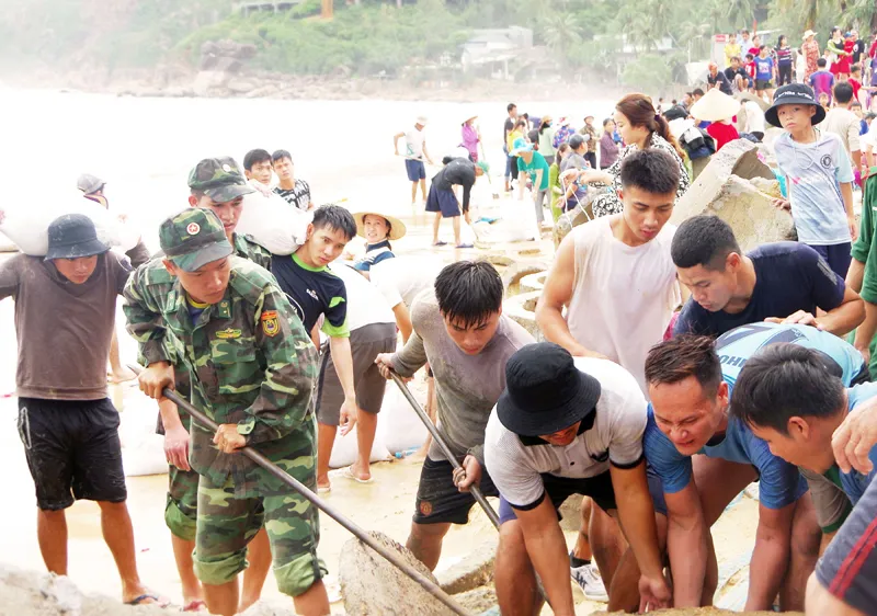 Lực lượng biên phòng, dân quân tự vệ và người dân nỗ lực sửa chữa kè biển xã Nhơn Hải, Bình Định. Ảnh: NGỌC OAI