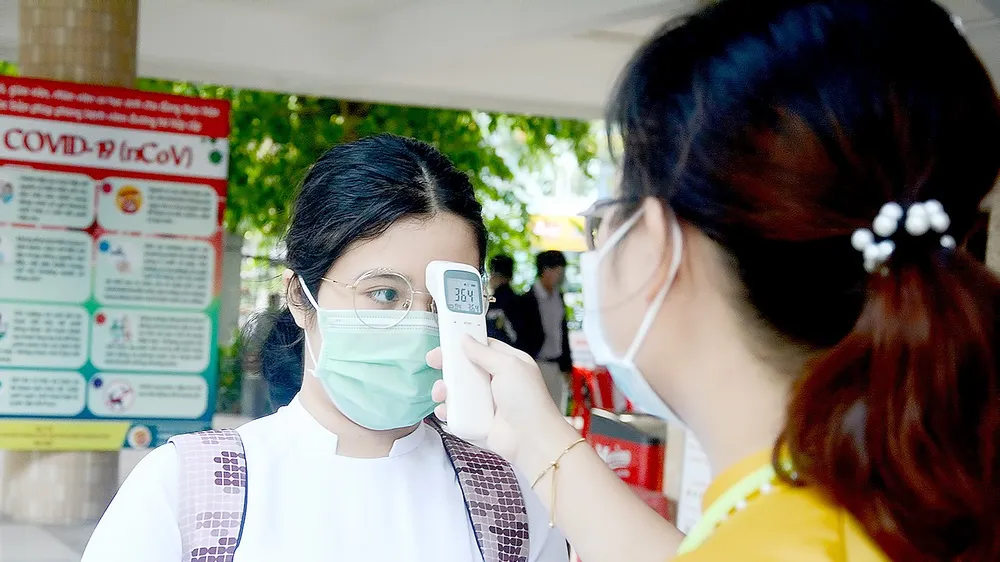 Giáo viên Trường THPT Phan Châu Trinh (quận Hải Châu, TP Đà Nẵng) kiểm tra thân nhiệt cho học sinh trước khi vào lớp. Ảnh: XUÂN QUỲNH