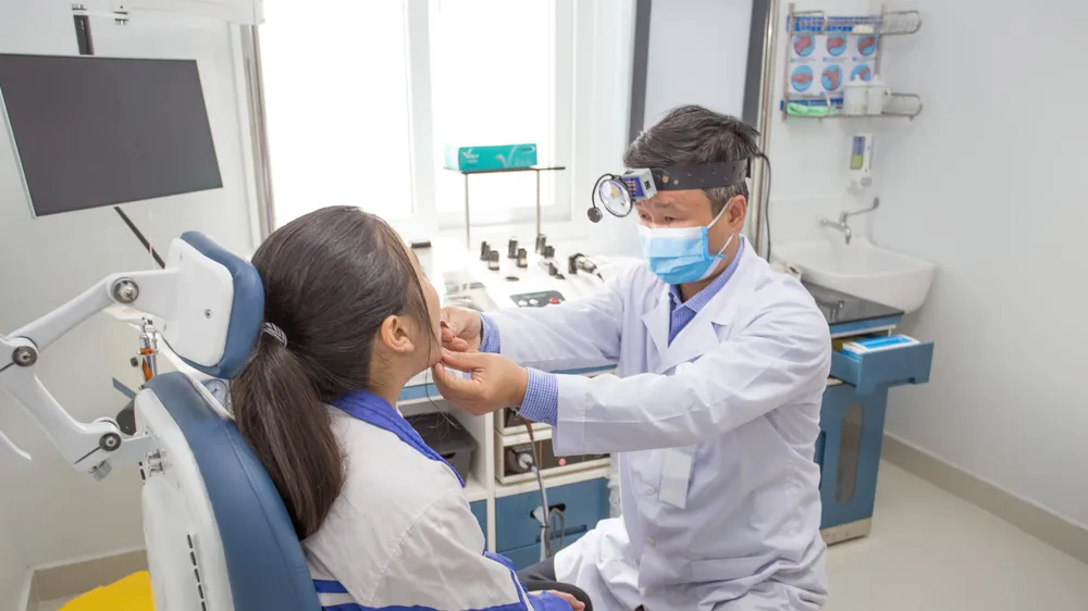 Bác sĩ khám họng cho một học sinh