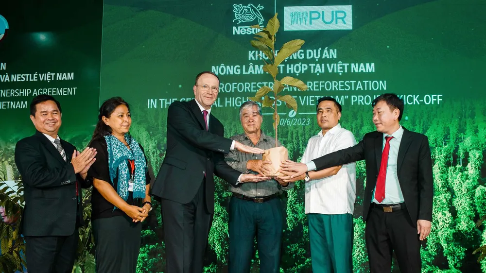 Ông Mark Schneider, Giám đốc điều hành Tập đoàn Nestlé (thứ 3 từ trái sang) trao cây đến người nông dân (thứ 4 từ trái sang), khởi động dự án nông lâm kết hợp tại Việt Nam