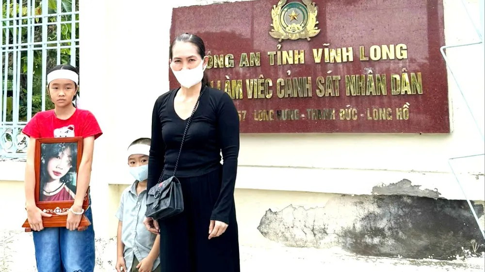Bà Hiền cùng 2 con nhỏ và di ảnh bé Bảo Tr., trước Công an tỉnh Vĩnh Long