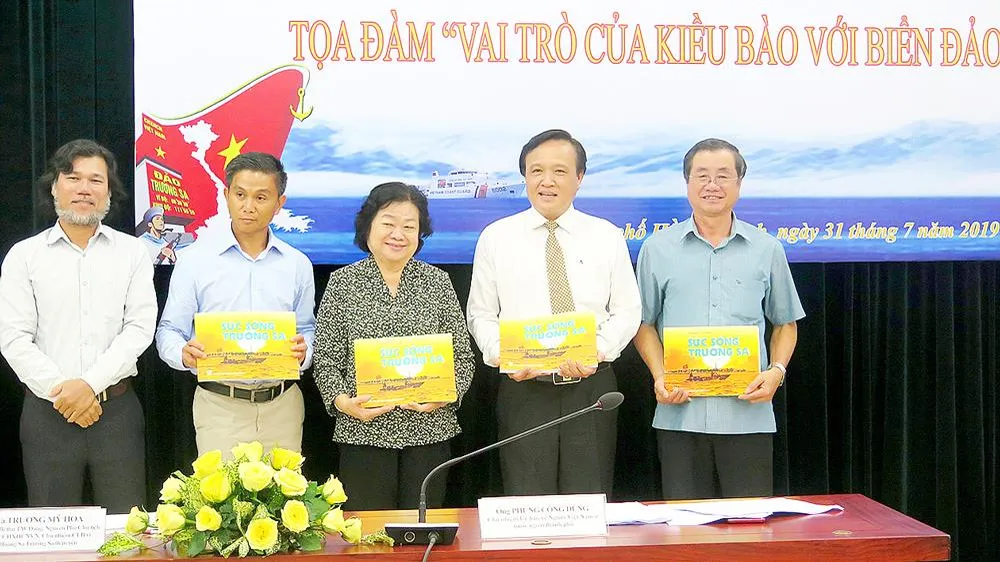 Ông Hoàng Chí Hùng (bìa trái), Chủ nhiệm CLB Ảnh báo chí Hội Nhà báo TPHCM, tặng các đại biểu sách ảnh về biển đảo