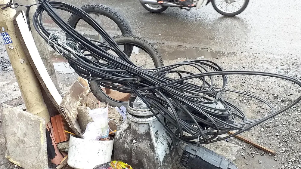 Bó dây điện cuộn dưới chân cột điện gây nhếch nhác, nguy hiểm