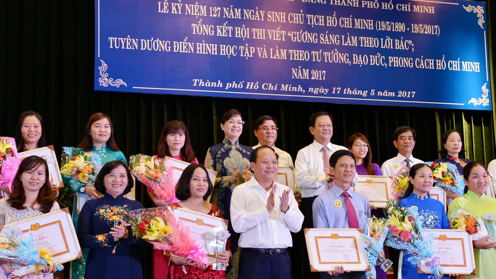 Phó Bí thư Thường trực Thành ủy TPHCM Tất Thành Cang cùng các đồng chí lãnh đạo TPHCM tuyên dương các tác giả đoạt giải tại hội thi “Gương sáng làm theo lời Bác” Ảnh: VIỆT DŨNG
