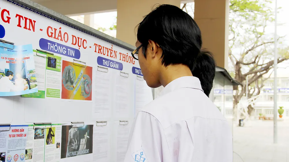Học sinh tìm hiểu cách phòng chống tác hại thuốc lá tại bảng tuyên truyền Ảnh: NGÔ ĐỒNG