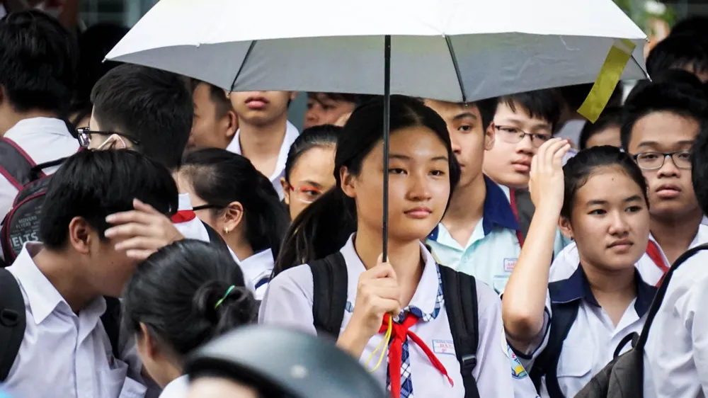 Thí sinh kết thúc thi môn Anh văn tại điểm thi Trường THCS ra về trong cơn mưa tầm tã