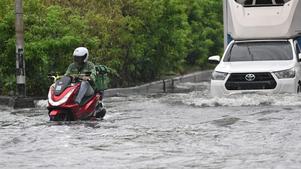 Một tài xế giao đồ ăn điều khiển xe máy băng qua vùng nước lũ ở Bangkok, Thái Lan, ngày 6-10. Ảnh: THX 