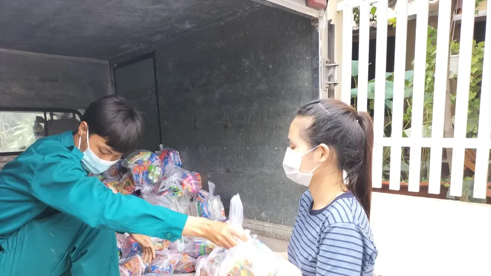 Người dân nhận nhu yếu phẩm do các nhà hảo tâm hỗ trợ. Ảnh: LÊ XUÂN
