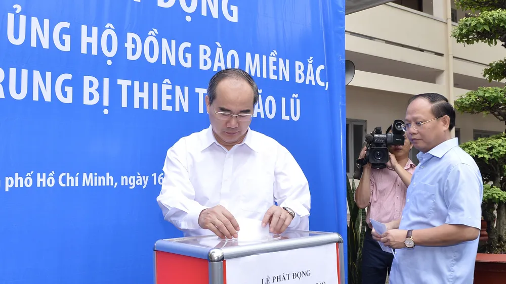 Bí thư Thành ủy TPHCM Nguyễn Thiện Nhân và Phó Bí thư Thường trực Thành ủy TP Tất Thành Cang đóng góp ủng hộ đồng bào vùng lũ. Ảnh: VIỆT DŨNG
