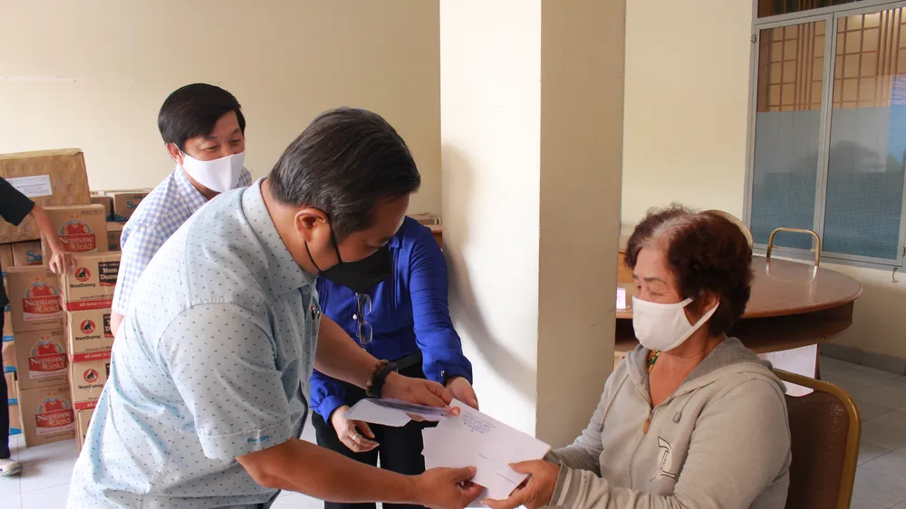 Phó Bí thư Thường trực Huyện ủy Hóc Môn Nguyễn Anh Tuấn trao tiền hỗ trợ cho người bán vé số lưu động. Ảnh: QUỲNH THY