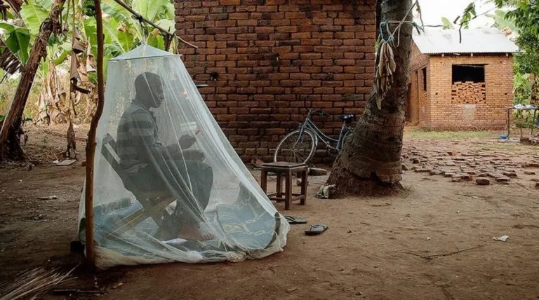 Một người dân ở Tanzania ngồi trong mùng để chống muỗi. Ảnh: Health Policy Watch