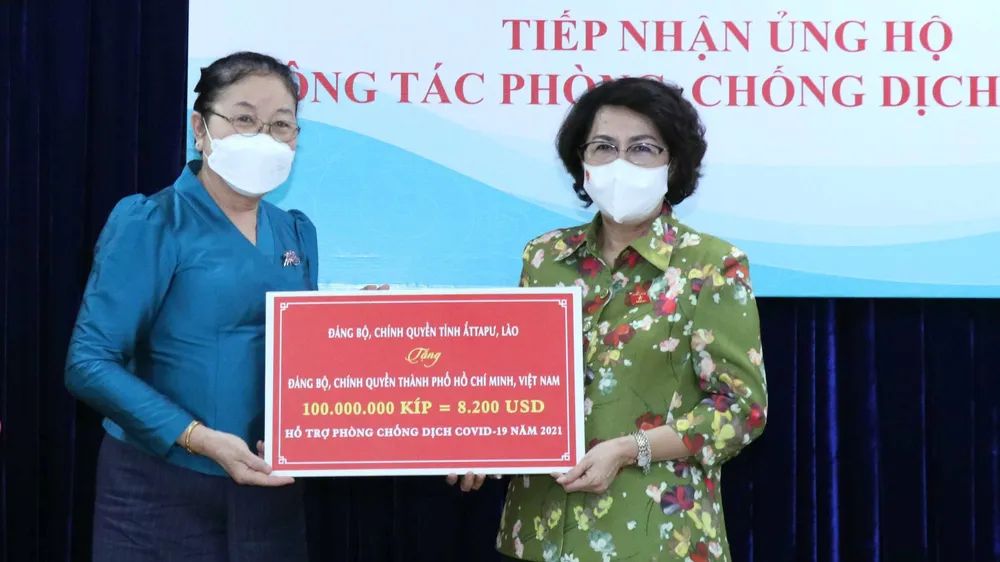 Chủ tịch Ủy ban MTTQ Việt Nam TPHCM Tô Thị Bích Châu tiếp nhận bảng tượng trưng ủng hộ do tỉnh Attapeu, Lào trao tặng