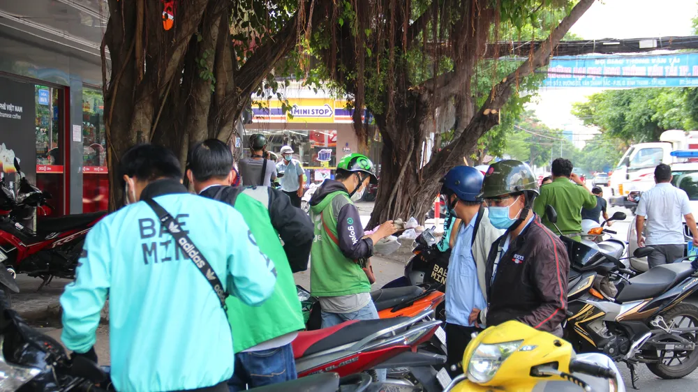 Nhiều tài xế xe công nghệ cùng shipper bị mời về phường vì vi phạm phòng chống dịch Covid-19. Ảnh: CHÍ THẠCH 
