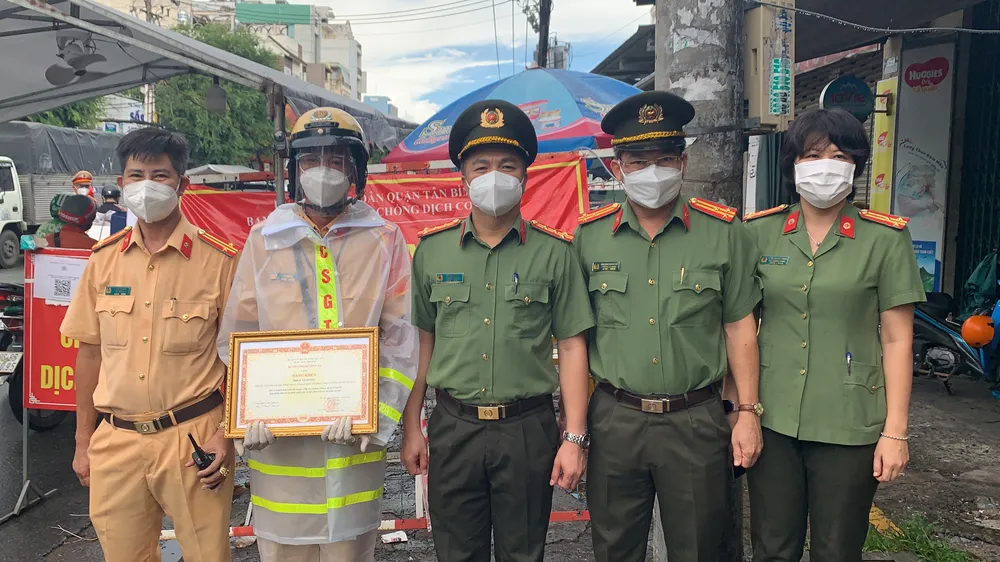 Đại tá Hoàng Văn Hà, Phó Cục trưởng Cục An ninh điều tra Bộ Công an (A09) trao tặng bằng khen cho Thiếu tá Lê Hoàng tại chốt kiểm soát phòng chống dịch. Ảnh: CHÍ THẠCH 