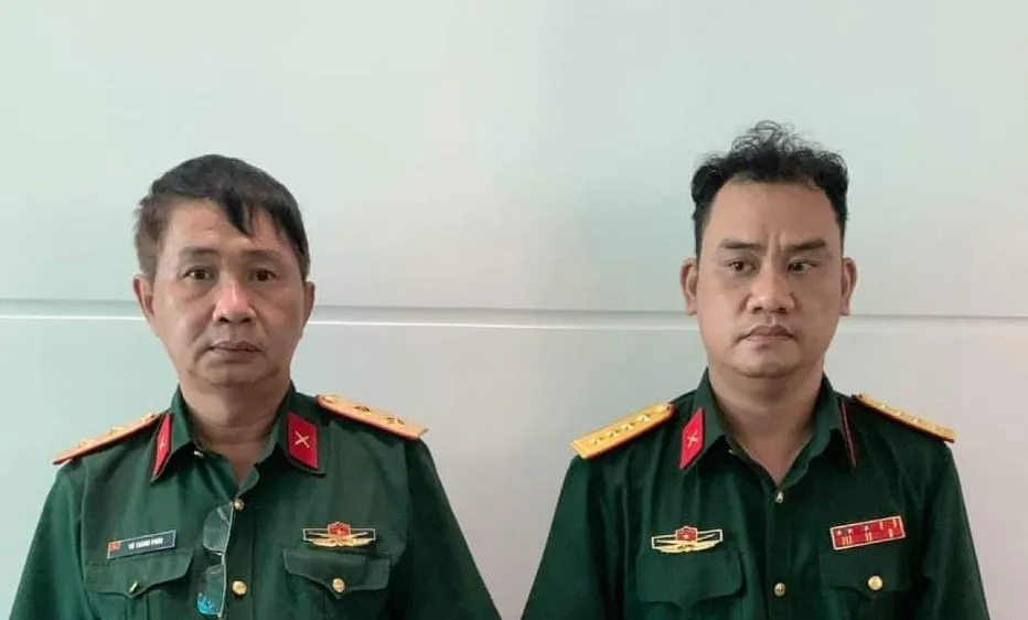 Võ Thành Phúc và Trần Vũ Hàn Minh Nhật (từ trái qua phải) cùng trang phục Quân đội tại cơ quan công an 