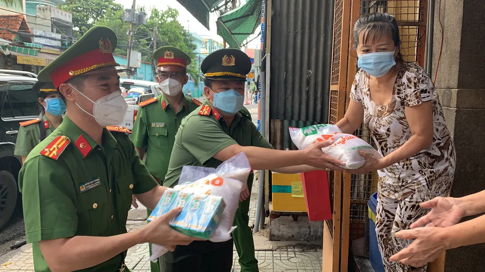 Thượng Tá Trần Anh Thanh, Phó Trưởng Phòng PX03, Công an TPHCM cùng Thượng tá Huỳnh Trung Phong, Trưởng Công an quận 6 gõ cửa nhà dân trao các phần quà hỗ trợ. Ảnh: CHÍ THẠCH 