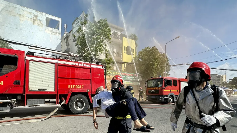Lực lượng chữa cháy cứu người mắc kẹt trong các căn nhà ra ngoài chuyển cấp cứu. Ảnh: CHÍ THẠCH