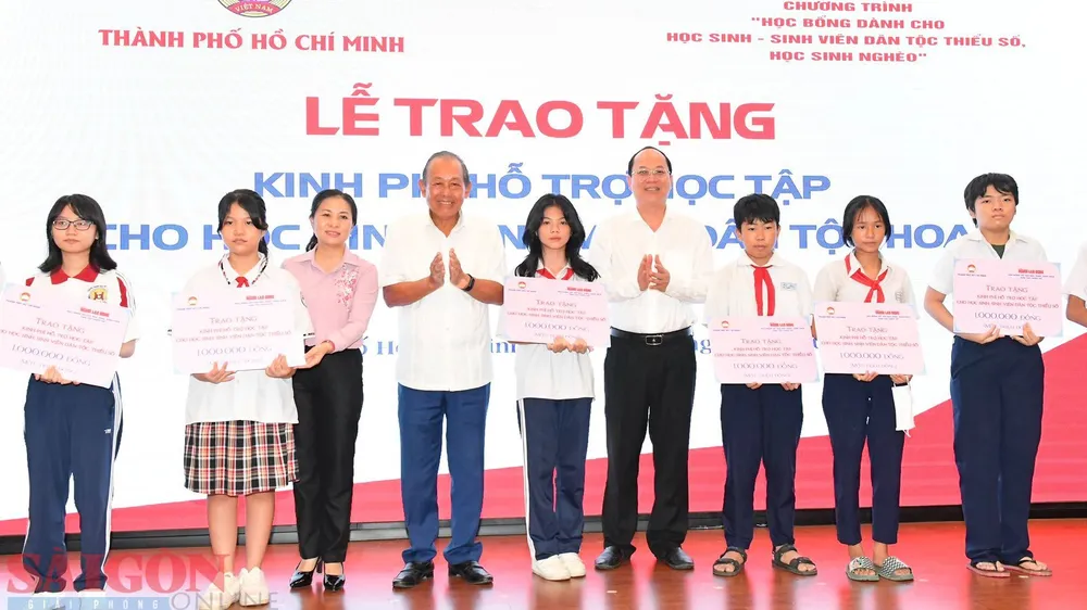 Phó Bí thư Thành ủy TPHCM Nguyễn Hồ Hải cùng nguyên Phó Thủ tướng Thường trực Trương Hòa Bình trao kinh phí hỗ trợ cho các em học sinh. Ảnh: VIỆT DŨNG 