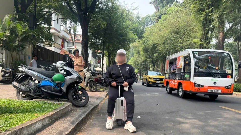 Người phụ nữ cưỡi vali chạy trên đường ở trung tâm TPHCM