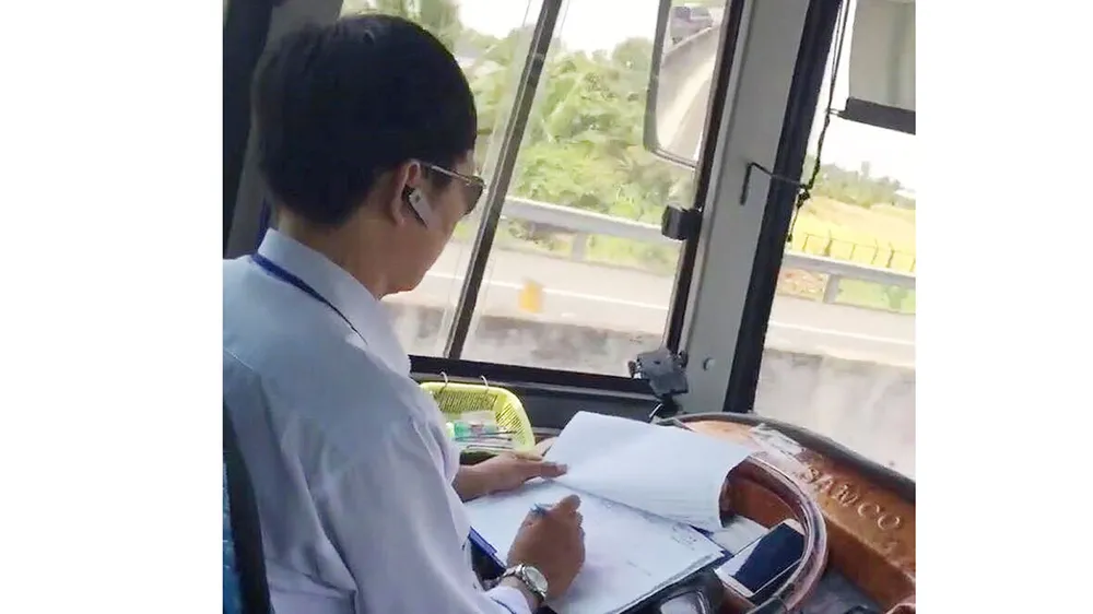 Tài xế vừa lái xe vừa xử lý giấy tờ (Ảnh cắt từ clip)