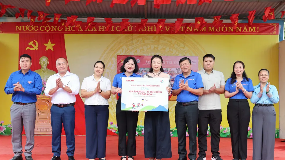 Đồng chí Tăng Hữu Phong, Phó Trưởng Ban Tuyên giáo Thành ủy TPHCM cùng Phó Tổng Biên tập Báo SGGP Bùi Thị Hồng Sương và lãnh đạo lãnh đạo xã Tràng Định tặng bảng biểu trưng áo ấm và học bổng cho lãnh đạo nhà trường. Ảnh: QUANG PHÚC
