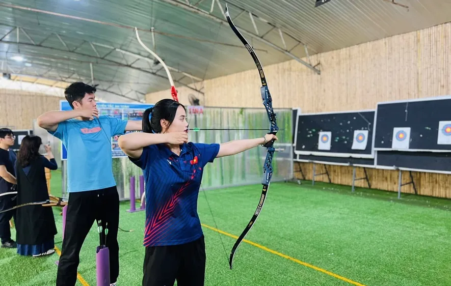 Ánh Nguyệt hướng dẫn Đức Phát làm quen với bắn cung để thêm hiểu hơn môn thể thao của mình. Ảnh: Đ.A.NGUYỆT