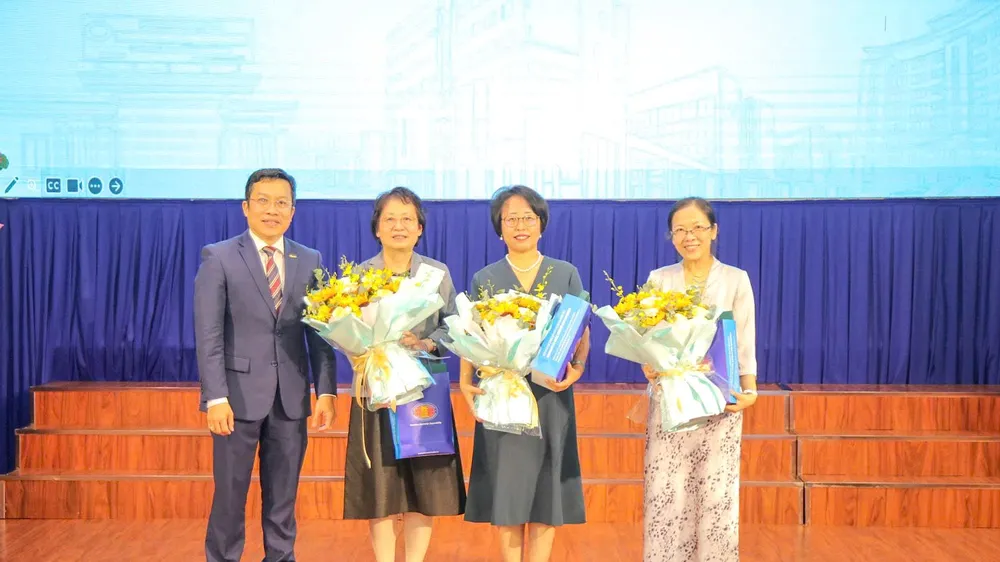 Đại diện Trường ĐH Khoa học xã hội và Nhân văn trao hoa và quà lưu niệm đến các chuyên gia tham gia tập huấn.