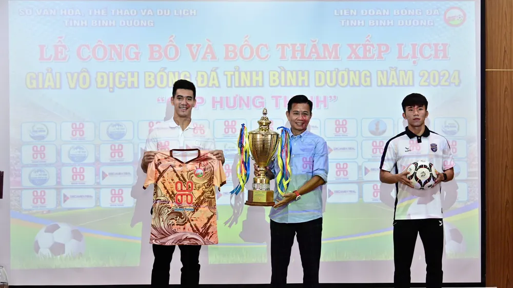 HLV Hoàng Anh Tuấn cùng cầu thủ Tiến Linh giới thiệu Cúp vô địch và áo thi đấu tại giải.