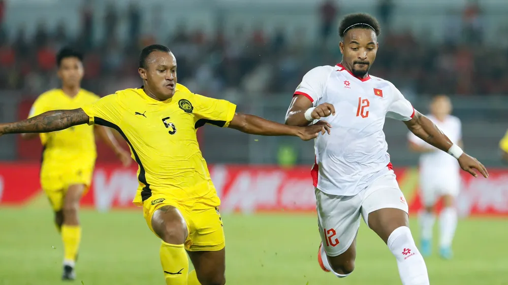 Rodney Celvin (áo vàng) của Malaysia tranh bóng với Xuân Son ở trận lượt đi (Ảnh: ANH KHOA)